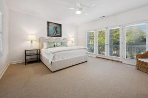 a white bedroom with a bed and windows at Poolside at DeBordieu Colony in Georgetown