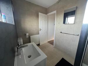 バーミンガムにあるTile Cross Entire Apartment - Near Airport, NEC & Moreの白い洗面台とシャワー付きのバスルーム