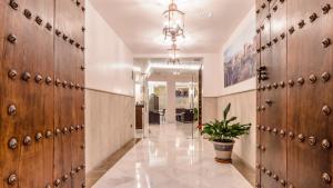 a hallway with wooden doors and a potted plant at Monjas del Carmen Hotel in Granada