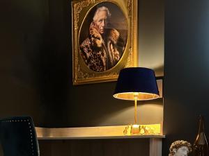 a portrait of a man in a painting next to a lamp at Amadeus Apartments in Douglas
