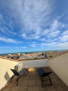 a patio with two chairs and a table on a roof at Mon Rooftop à la Plage in Frontignan