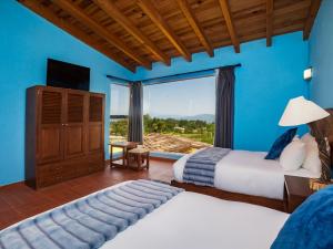 a bedroom with two beds and a large window at Hotel Campestre, Valle de Bravo in Valle de Bravo