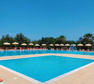 a large swimming pool with chairs and umbrellas at La Porta del Sole Hotel & Village in San Ferdinando