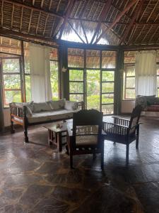 a living room with a couch and chairs and windows at Red Sunshine Villa B&B in Malindi