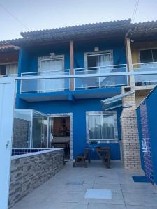 une maison bleue avec un balcon et un patio dans l'établissement Unamar, conforto em frente a praia!, à Cabo Frio