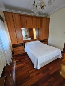 Un dormitorio con una gran cama blanca y armarios de madera. en TATI HOMES - Caleruco 50, en Santander