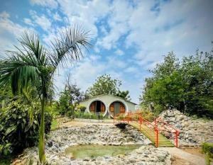 a house with a bridge over a pond at Van Vagdo Resort in Bhanadra