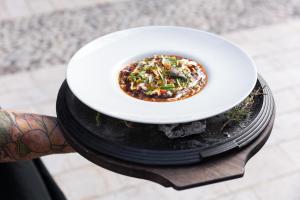 a person holding a plate of food on a table at Il Grottino Relais & Spa in Gualdo Cattaneo