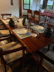 a wooden table with plates and glasses on it at Red Sunshine Villa B&B in Malindi