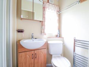 a bathroom with a sink and a toilet and a mirror at 120 Caravan in Great Yarmouth +5 photos