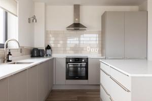 a kitchen with white cabinets and a black oven at Leenan at Ballyliffin Beach Houses, Pollan Bay in Ballyliffin