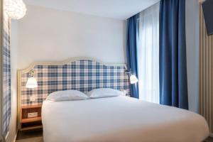 Un dormitorio con una cama blanca con cortinas azules. en Hotel Boris V. by Happyculture, en Levallois-Perret