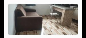 a living room with a chair and a couch and a counter at Linda kitnet estilo loft! unidade 2 in Guarapuava