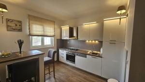 una cocina con armarios blancos, una mesa y una barra en Apartman SeaShell, en Primošten