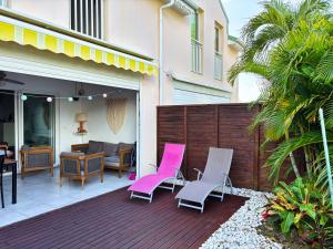 a patio with pink and white chairs on a deck at Ti Kaz in Saint-François