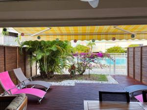 a patio with pink chairs and a pool at Ti Kaz in Saint-François