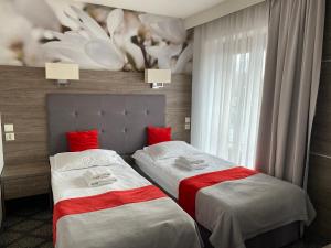 2 łóżka w pokoju hotelowym z czerwonymi poduszkami w obiekcie Pass Hotel w mieście Zebrzydowice