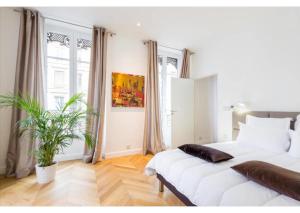 a bedroom with a large white bed and a plant at Appartement de luxe Place Bellecour in Lyon