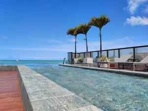 若昂佩索阿Flat Vista Mar em Manaíra Arpoar by Qavi的有棕榈树和大海的游泳池