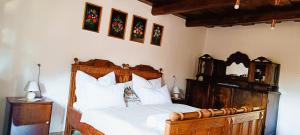 a bedroom with a wooden bed with white sheets at Vándor Kakas Vendégház dézsafürdővel in Recsk