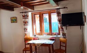 uma sala de estar com uma mesa, uma televisão e uma janela em Vándor Kakas Vendégház dézsafürdővel em Recsk mais 32 fotografias