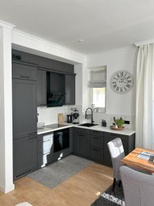 a kitchen with gray cabinets and a clock on the wall at Kaiserhof Apartment 14 in Wangerooge