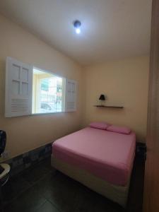 a bedroom with a bed with pink sheets and a window at Apartamento Favo de Mel 1 in Suape