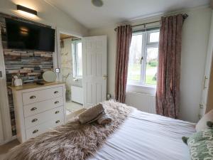 a bedroom with a bed and a dresser and a television at Our Happy Place in Carnforth