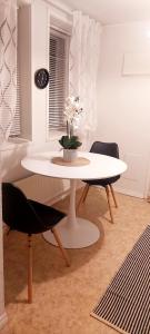 a white table with a vase of flowers on it at Huoneisto Pikku Neristan in Kokkola