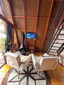 a living room with two chairs and a tv at Cabana Fé in Nonoai