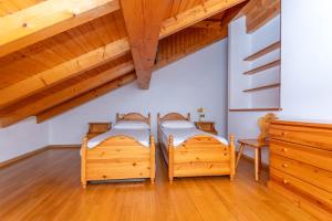 two beds in a room with wooden ceilings at Villa Eden in Falcade