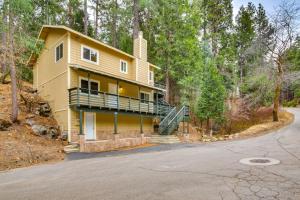 a yellow house with a balcony in the woods at 4 Mi to Lake Arrowhead Cabin with Grill and Deck! in Twin Peaks