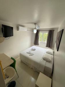 a bedroom with a white bed and a television at Esquina Batel - Hotel Econômico in Curitiba +80 photos