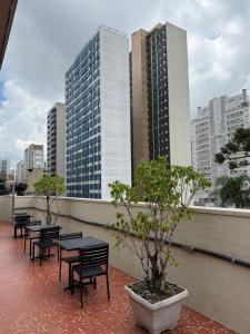 a row of tables and benches on a balcony with buildings at Esquina Batel - Hotel Econômico in Curitiba