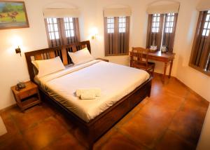 a bedroom with a bed and a desk and windows at Sarada Mandiram A Heritage Hotel in Cochin