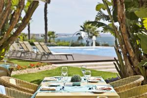 a table with wine glasses on it next to a pool at Hotel Cascais Miragem Health & Spa in Cascais
