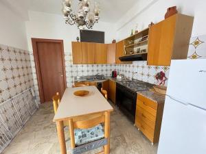 a kitchen with a table and a white refrigerator at APT Via Calabria 6da Francesca in Marina di Monasterace