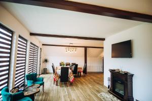 a living room with a fireplace and a dining room at Aframe LINIȘTEA PĂDURII NĂMĂEȘTI in Nămăeşti