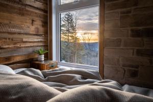 a bed in a room with a window with a view at CHAMONIX - Micro Chalet with Panoramic Mountain Views near Québec in Lac-Beauport
