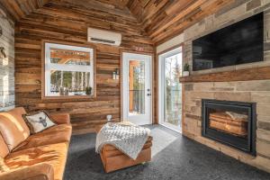 a living room with a fireplace and a tv at CHAMONIX - Micro Chalet with Panoramic Mountain Views near Québec in Lac-Beauport