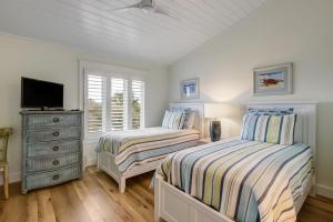 two beds in a bedroom with a tv and a dresser at 608 Sailmaker in Fernandina Beach +30 photos