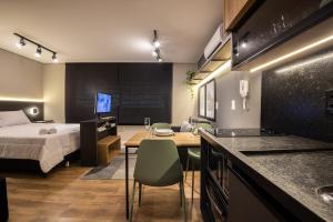 a bedroom with a bed and a desk and a kitchen at Loft 613 Canto com garagem in Pelotas