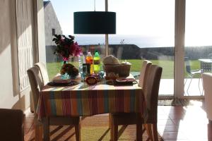 a dining room table with a colorful table cloth and flowers at Vivenda Vista Mar 8 in Caloura