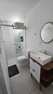 a bathroom with a sink and a toilet and a mirror at Pousada Bahamas Sc in Penha