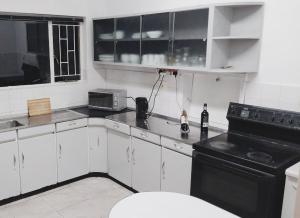 a kitchen with white cabinets and a black stove at Cozy Retreat Ferndale in Johannesburg