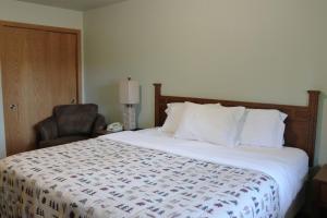 Ce lit se trouve dans une chambre d'hôtel dotée d'une chaise et d'un couvre-lit. dans l'établissement 2 Bedroom Condo at Wild Eagle Lodge, #229, à Eagle River