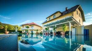 a swimming pool in front of a house at Dorf Hotel Grüner Baum in Maria Laach am Jauerling