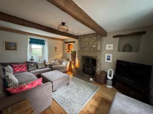 un salon avec un canapé et une cheminée dans l'établissement Prior Hall Farm Cottage - 3 bedroom luxury cottage in center of Malham, à Malham