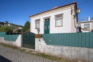 a house with a green gate and a fence at Casa das Camélias Tortas in Castanheira de Pêra