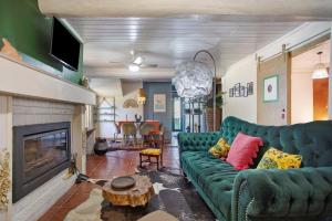 a living room with a green couch and a fireplace at Casa das Camélias Tortas in Castanheira de Pêra